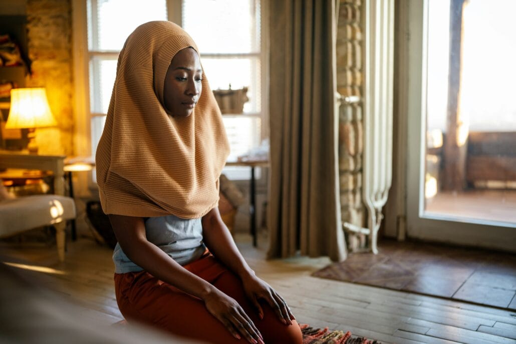 Young muslim black woman praying at home