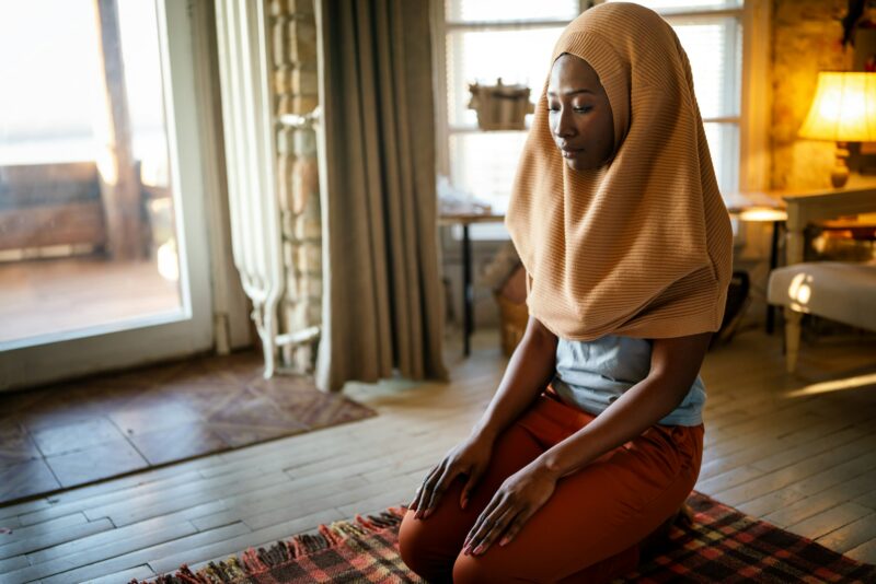 Young muslim black woman praying at home