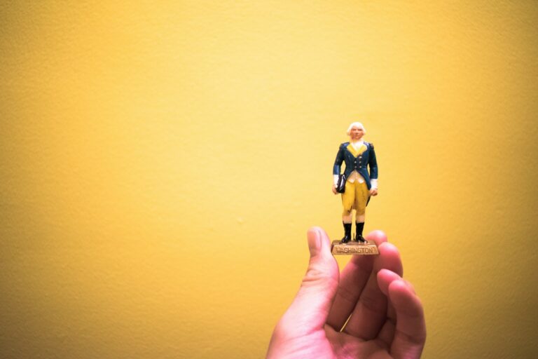 person holding man wearing black suit figurine