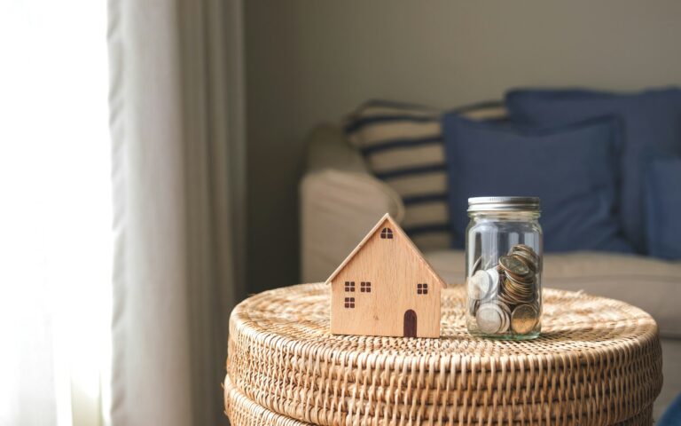 A wooden house model and a glass jar of coins for saving money concept