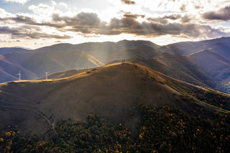 Aerial shot of a landscape and a wind turbine on a mountain