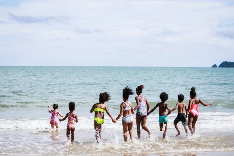 African American, Kids group enjoying running to play the waves on beach. Ethnically diverse concept