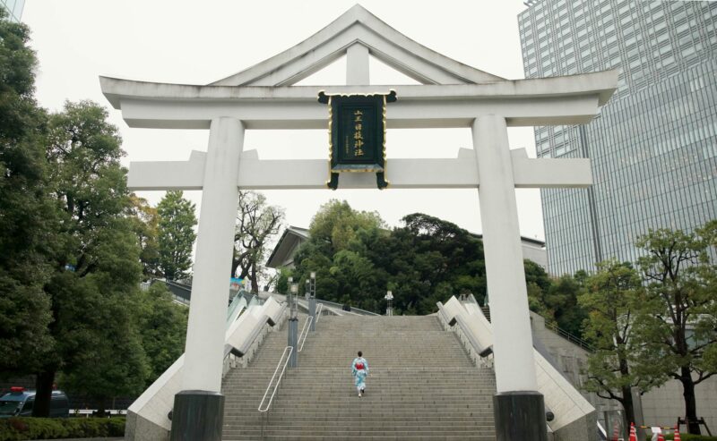 Back, shrine and steps with Japanese woman walking in city temple for belief, faith or religion. Bu