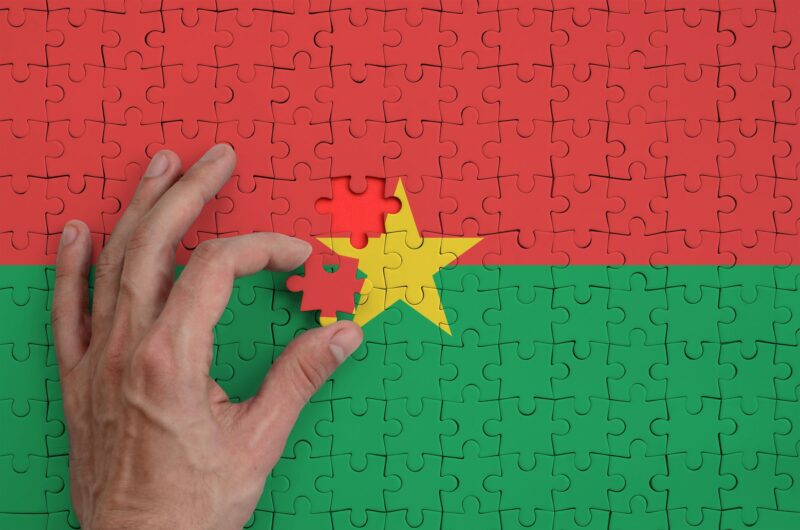Burkina Faso flag is depicted on a puzzle, which the man's hand completes to fold.