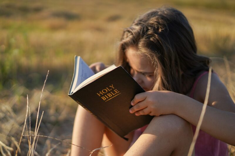 Christian girl holds bible in her hands. Reading the Holy Bible in a field. Concept religion.