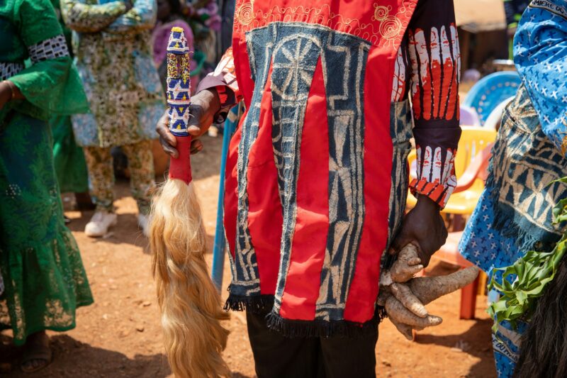 Close-up of African dress worn by a gentleman holding a traditional decorative ponytail and tuber