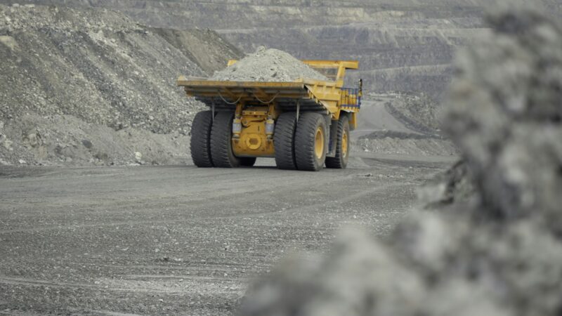 Close-up of dump truck moving on a quarry road loaded with ore. Back view.
