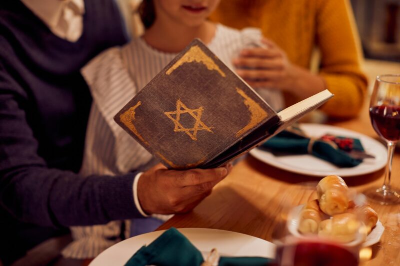 Close-up of Jewish family reading Tanakh at dining table on Hanukkah.