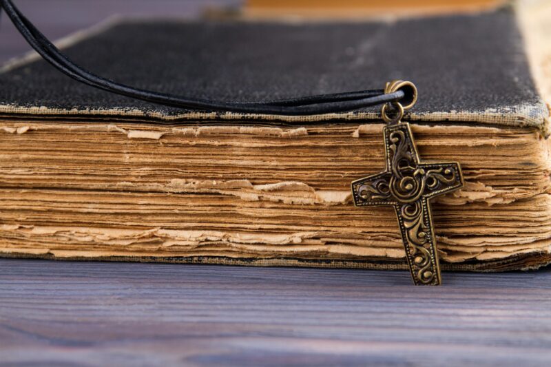 Closeup of christian cross with on holy Bible with a black cover.