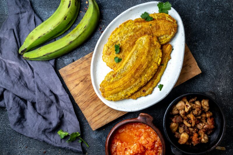 Colombian Patacon or toston, fried and flattened whole green plantain banana on white plate
