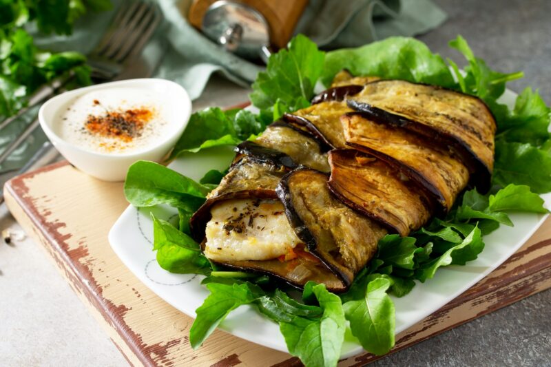 Delicious fish baked with vegetables in an eggplant grilled on a stone or slate table.