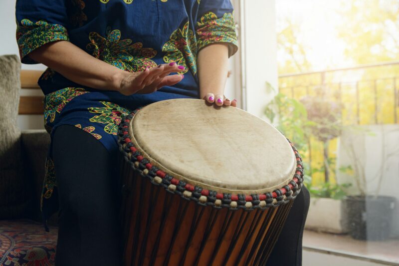 Female hands of an unrecognizable woman playing the Djembe drum in home