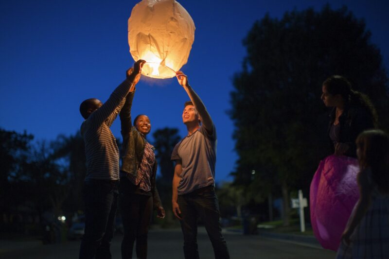 Friends holding up sky lantern to celebrate