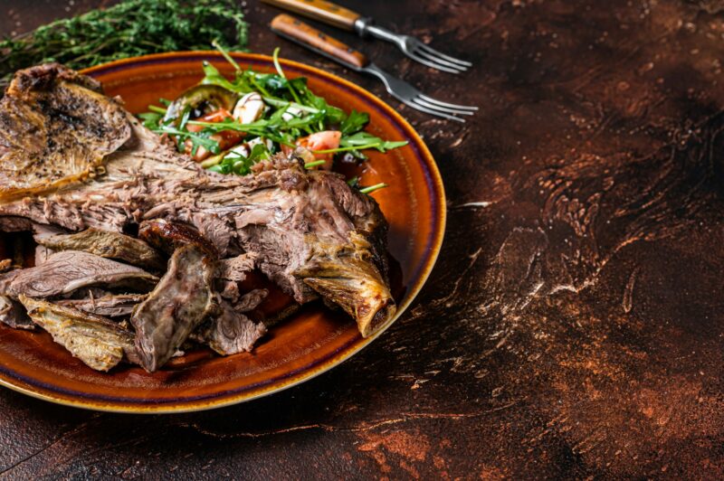 Grilled goat or lamb mutton shoulder meat in a rustic plate with salad.