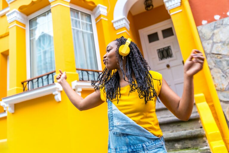 Happy african woman dancing listening to music with headphones outdoors