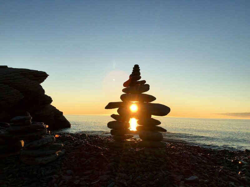 Inukshuk sculpture built at the edge of ocean and glowing in the rays of rising sun