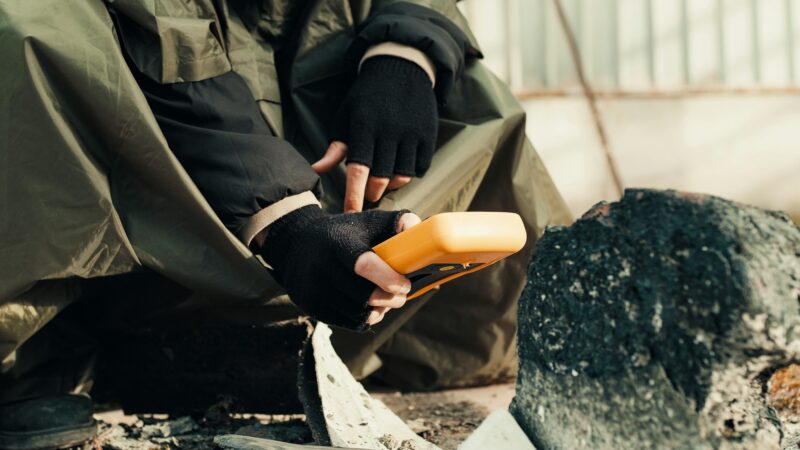 man with geiger counter near radioactive waste