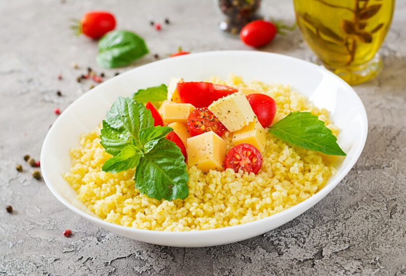 Millet porridge with cheese, butter and basil in white bowl. Tasty food. Breakfast.