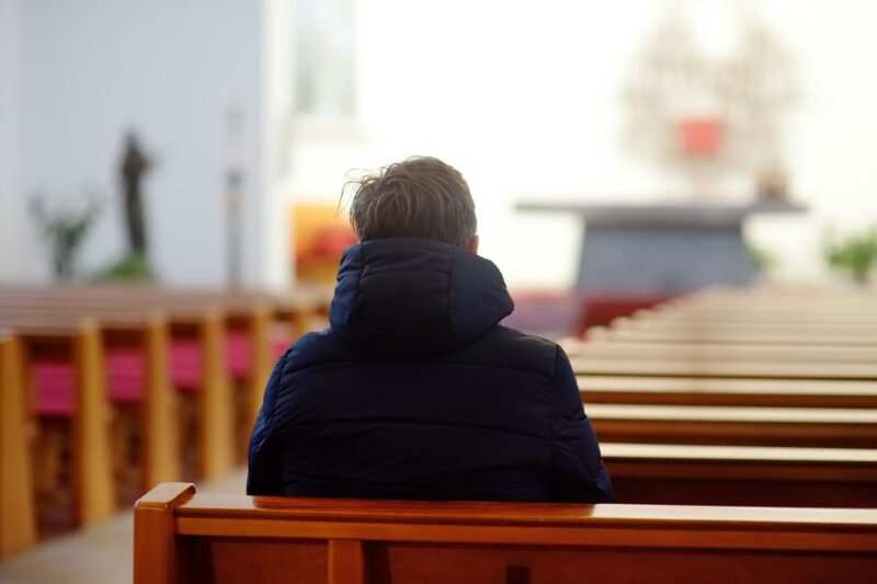 Religious middle age man praying and meditating in catholic church. Person begging for forgiveness