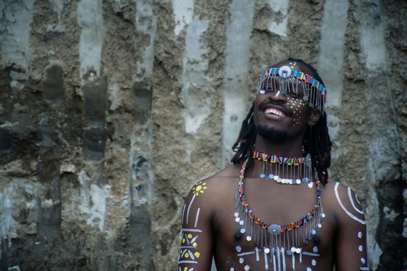 a man wearing a headdress standing in front of a stone wall