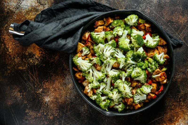 Roasted chicken meat with root vegetables on pan. Dark background. Top view