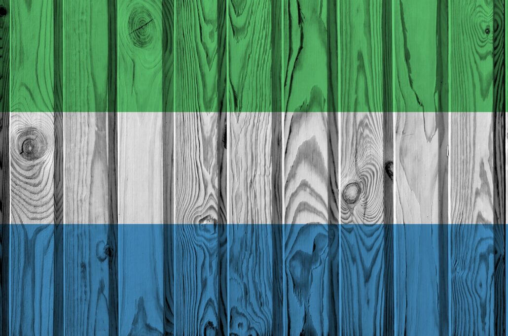 Sierra Leone flag depicted in bright paint colors on old wooden wall close up
