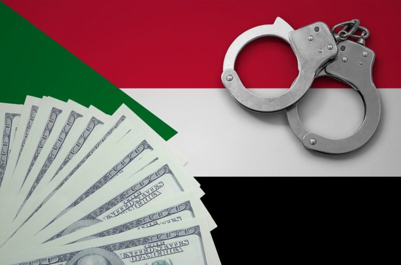 Sudan flag with handcuffs and a bundle of dollars