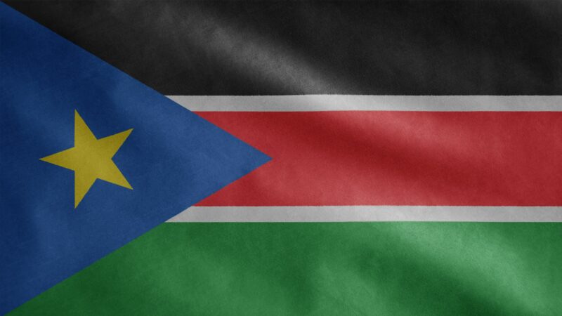 Sudanese flag waving in the wind. Close up South Sudan banner blowing soft silk.