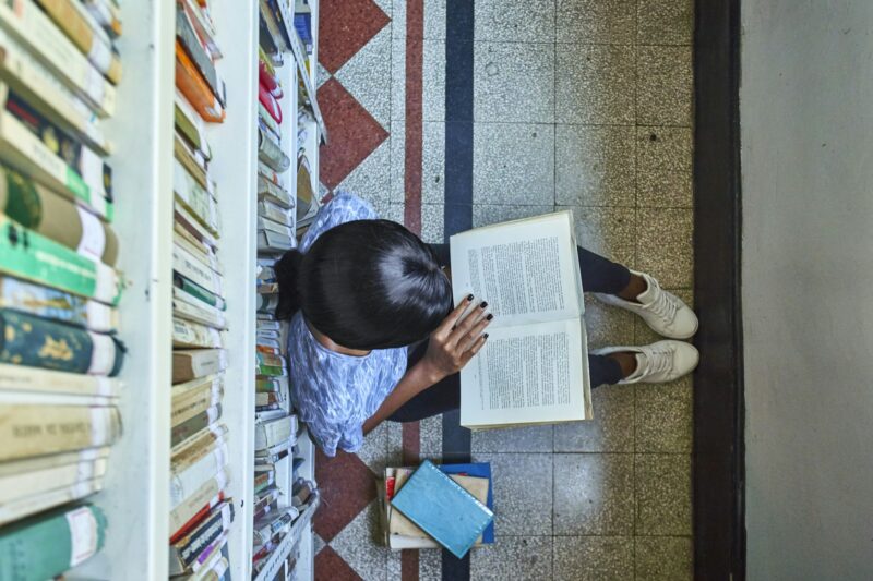 Top view of young woman sitting on the floor reading a book at National library, Maputo, Mocambique