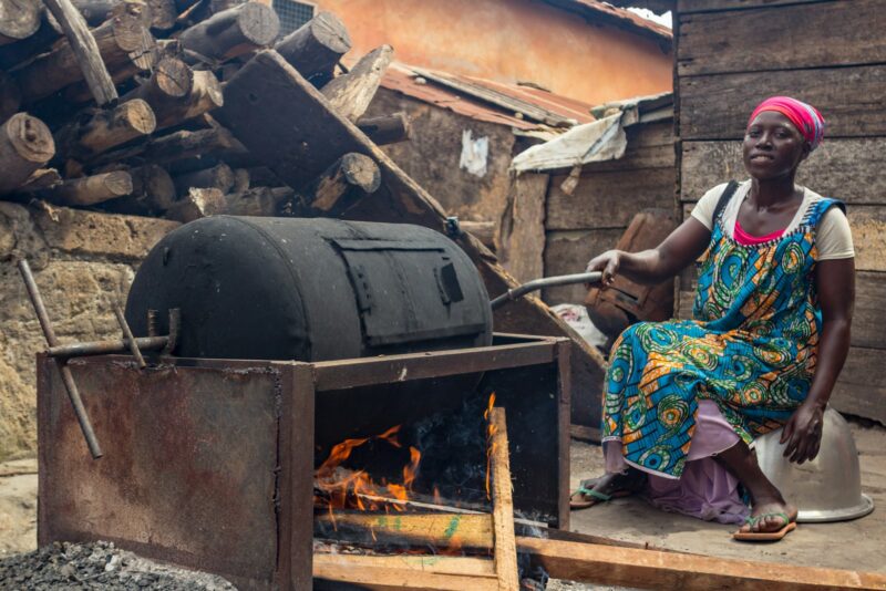 a woman sitting next to an open fire pit