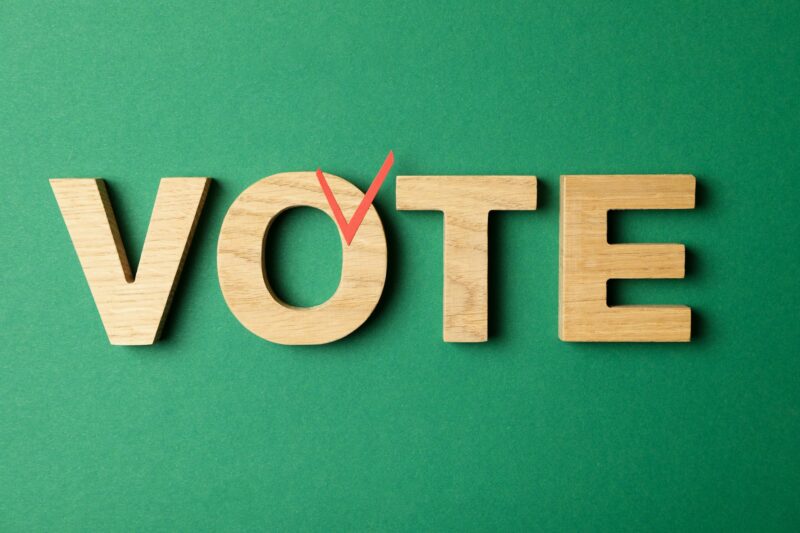 Word Vote made of wooden letters on green background