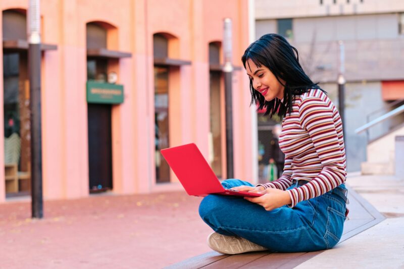 young brunette moroccan student using laptop computer outdoors