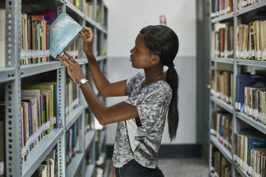 Young woman checking the books at the bookshelves at National library, Maputo, Mocambique